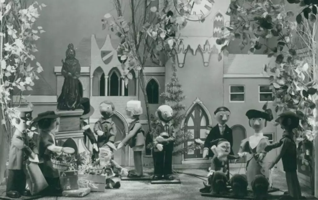 Characters from the TV show Camberwick Green stand in the Fenwick Window Display. They cluster outside a model of a festive church. This was the first Fenwick window display in 1971.