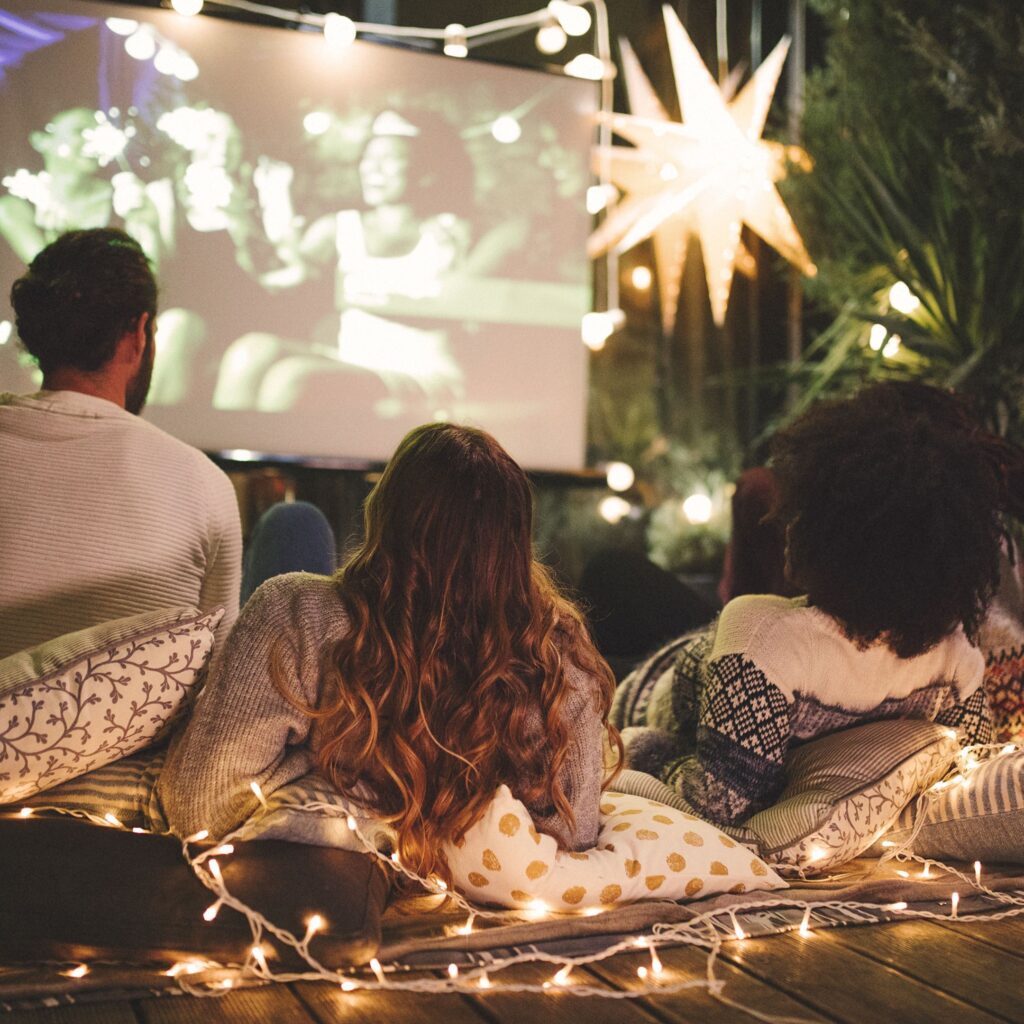 A few friends lay down on their backs to watch a festive Christmas movie on the projector