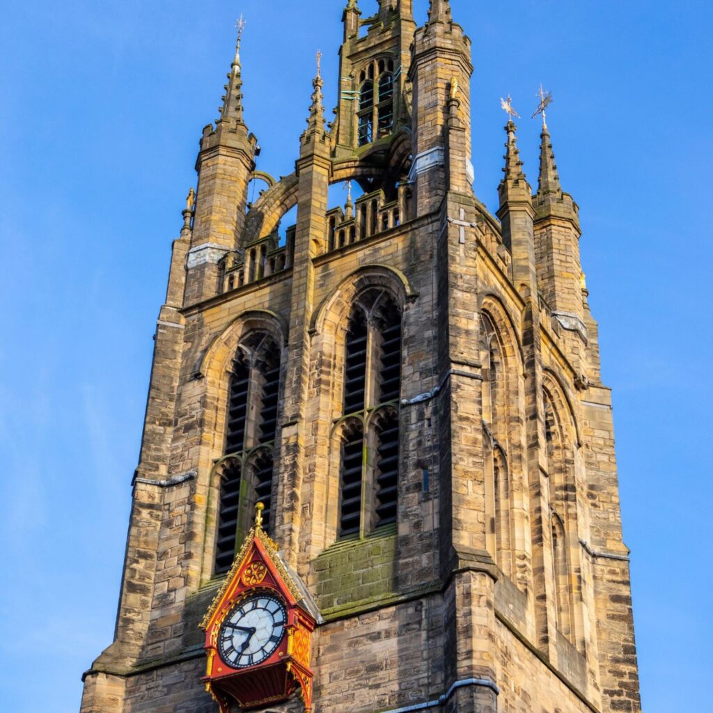 Newcastle Cathedral's spire against a bright blue sky.