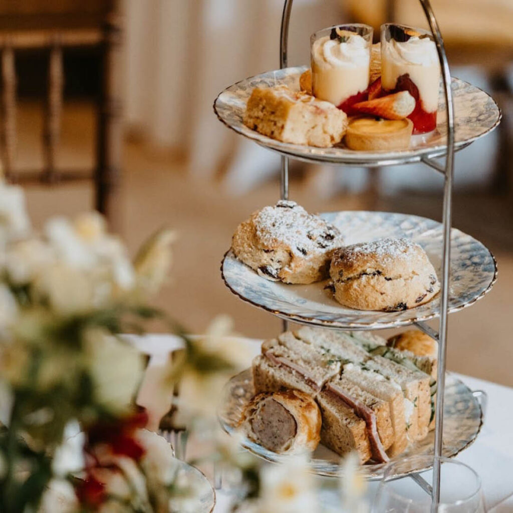 Three tiers of scones, cakes, pastries and sandwiches on delicate plates.