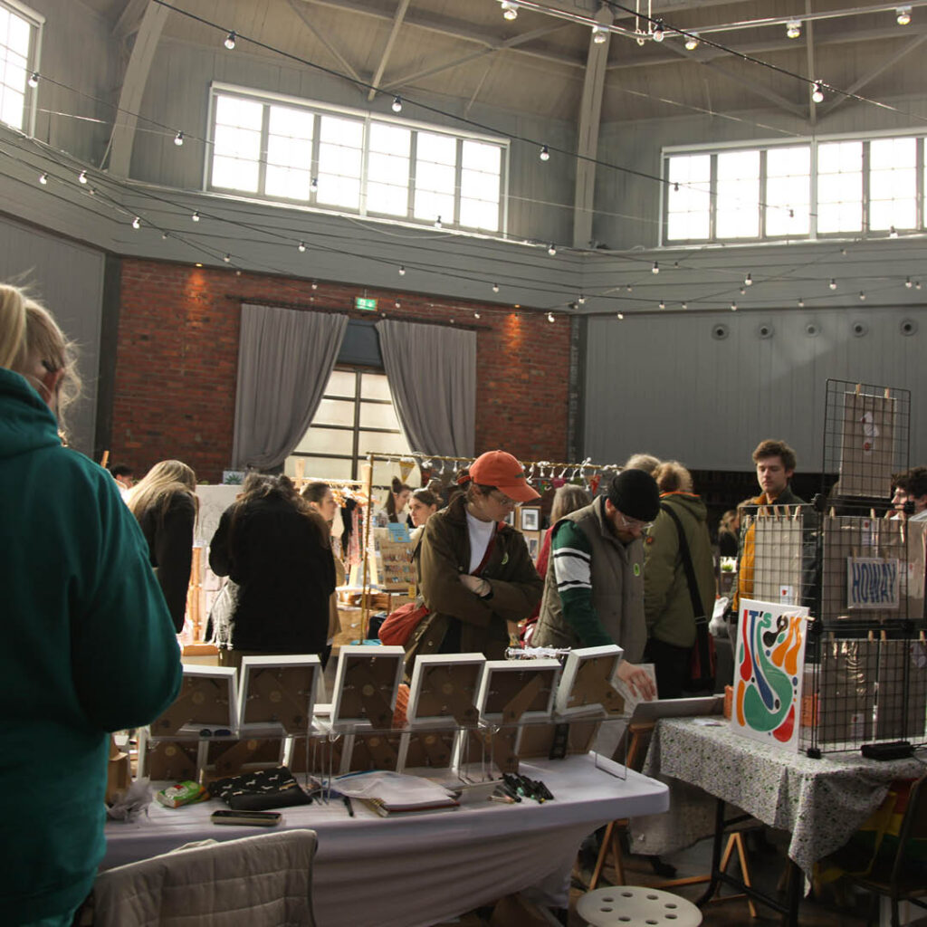 People browse various stalls at the Crafty Bazaar at Wylam Brewery. Pretty fairy lights hang from the roof.