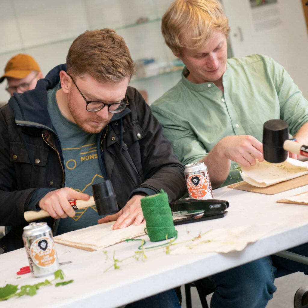 Two men lean over a table in concentration as they get stuck into a craft activity at one of the Discovery Museum's Discovery Nights.
