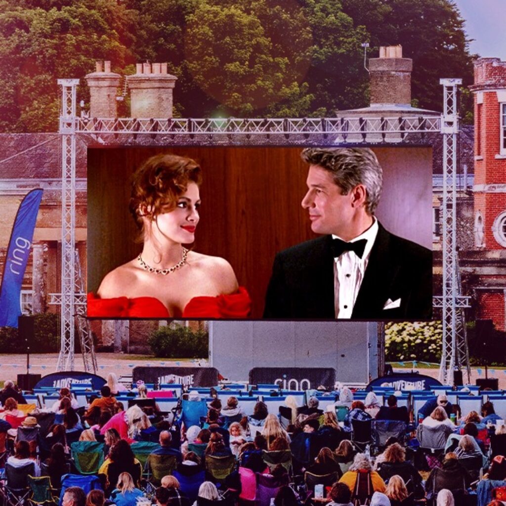 Pretty Woman plays on a big open-air screen in the grounds of Alnwick Castle. People sit in front of it on camping chairs.
