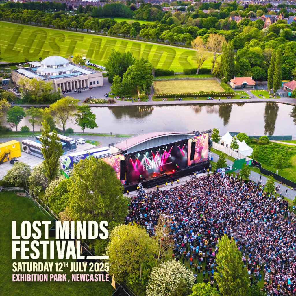 Aerial view of a main festival stage with thousands of people gathered in front of it as pink strobelights glow. The stage is surrounded by green fields, trees and a lake. White text says: Lost Minds Festival. Saturday 12th July 2025, Exhibition Park, Newcastle.