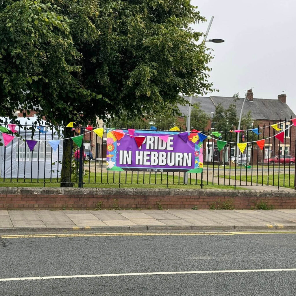 Rainbow bunting is strung across the black railing around Hebburn's Fountain's Park. A purple banner reads: Pride in Hebburn.