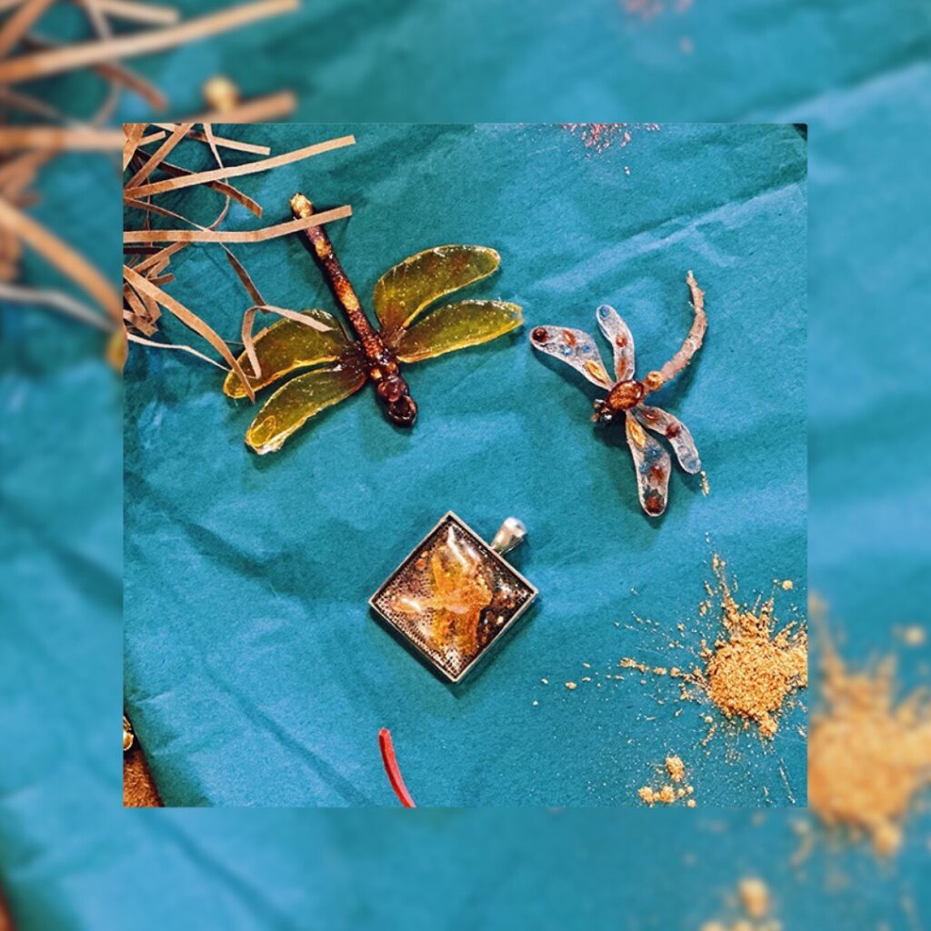 Small resin dragonfly shaped charms against a blue paper background.