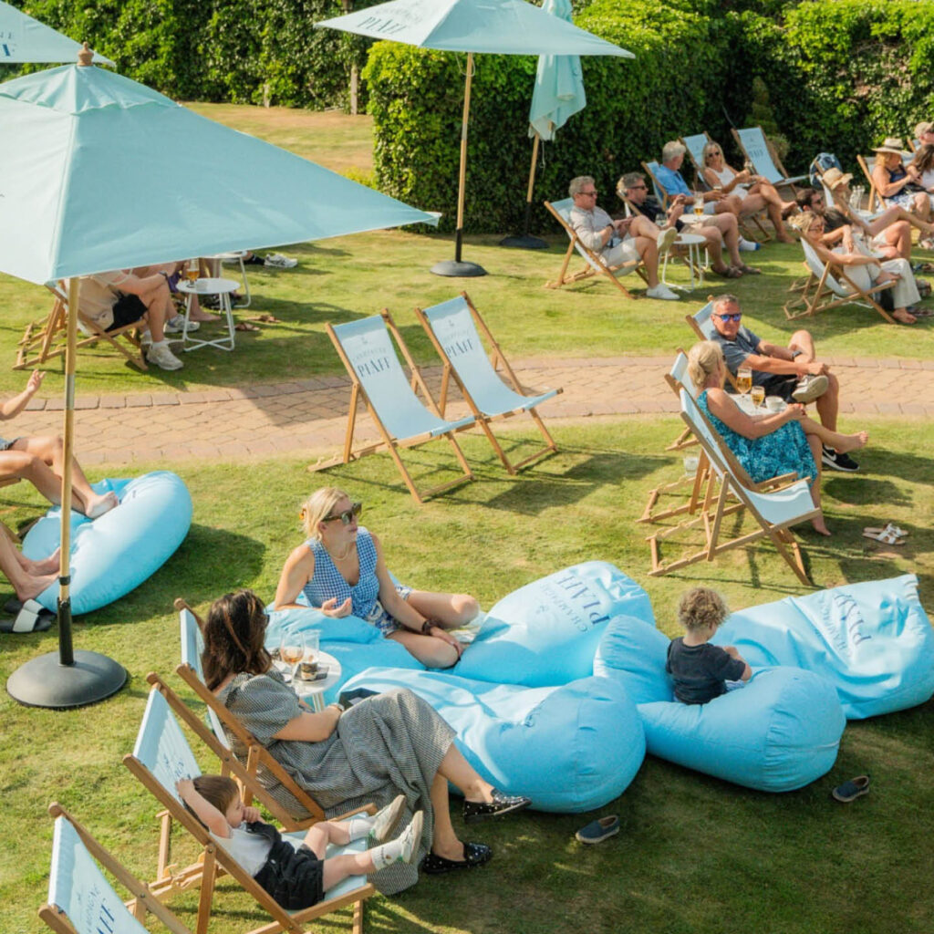People lounge on blue deck chairs and bean bags scattered across the lawn at Rockliffe Hall. They are there to watch a film on the Screen on the Lawn.