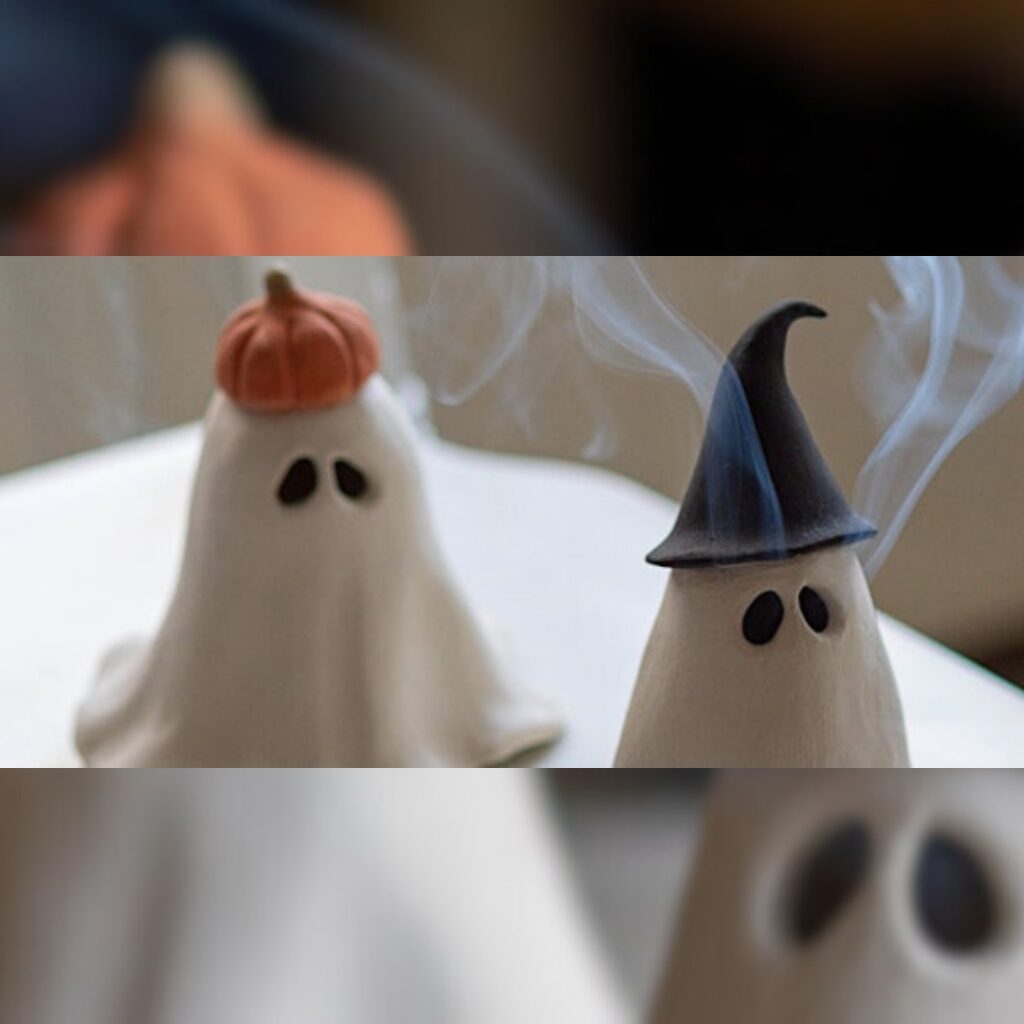 Two cute clay ghosts, one wearing a pumpkin hat and other wearing a witch's hat. Incense smoke rises from their hollow eyes.