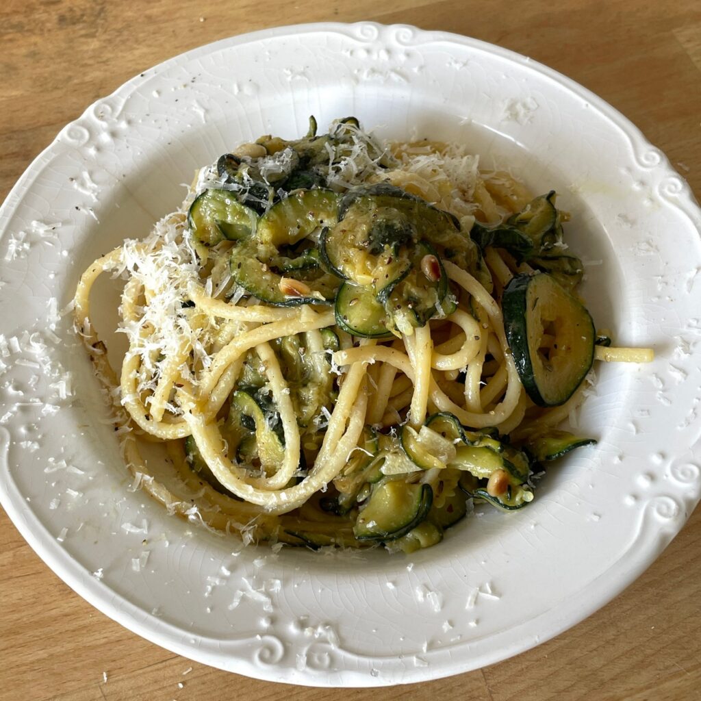 A bowl of creamy courgette, pine nut and lemon linguine topped with freshly grated parmesan. Thinly sliced courgettes are cooked until soft and silky, creating a light, creamy sauce without cream.