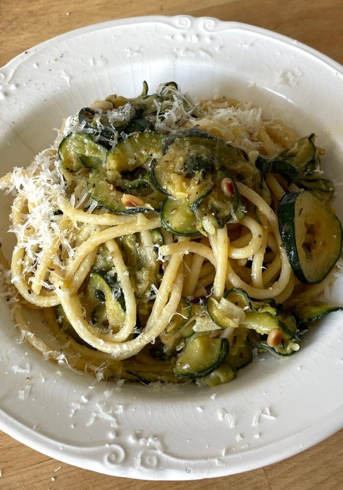 A bowl of creamy courgette, pine nut and lemon linguine topped with freshly grated parmesan. Thinly sliced courgettes are cooked until soft and silky, creating a light, creamy sauce without cream.